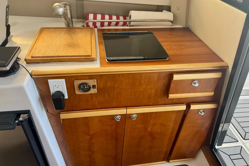 Slide: The Image of 2021 Cutwater C-24 Coupe interior kitchen with wooden cabinetry and modern appliances. - 28