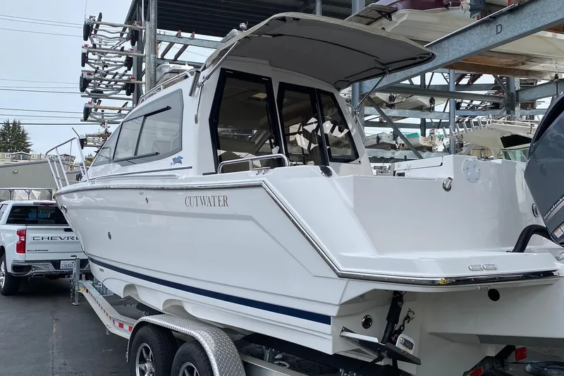 Slide: The Image of 2021 Cutwater C-24 Coupe boat on trailer, parked near a Chevrolet truck. - 7
