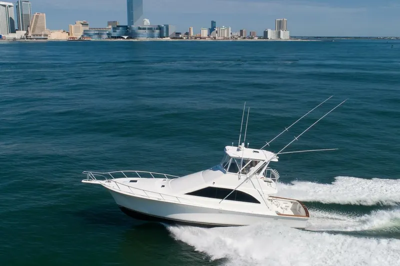 Slide: The Image of 1999 Ocean Yachts 48 Super Sport cruising on ocean near city skyline. - 21