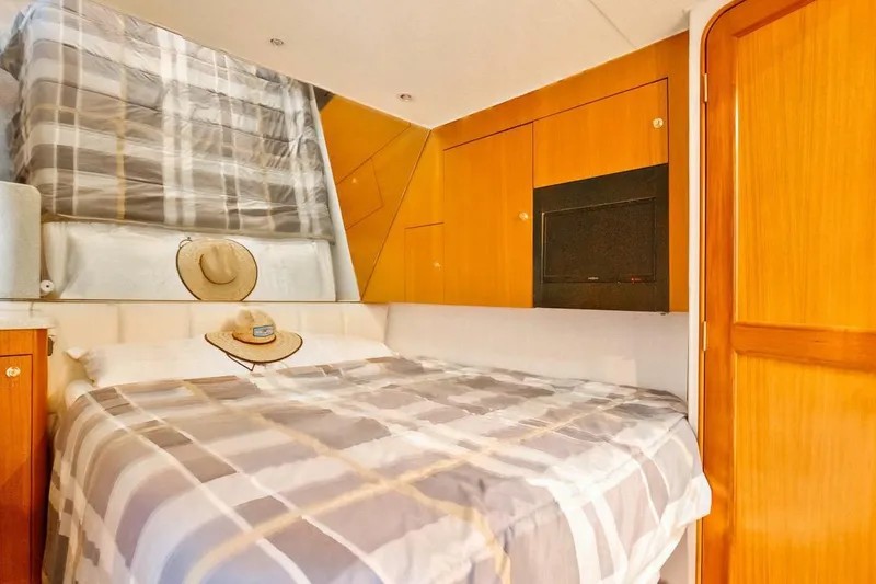 Slide: The Image of Cozy bedroom in 1999 Ocean Yachts 48 Super Sport with plaid bedding and wooden cabinetry. - 10
