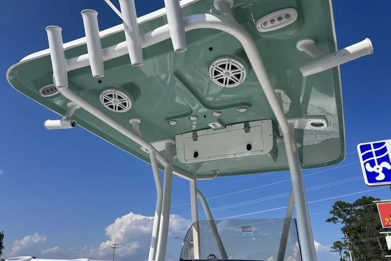 Slide: The Image of 2026 Sea Hunt Ultra 219 boat T-top with rod holders and speakers against blue sky. - 10