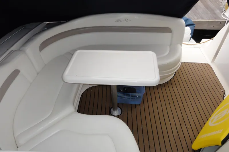 Slide: The Image of 2004 Sea Ray 320 Sundancer interior with white seating and table on wooden deck. - 15