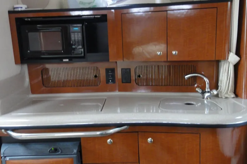 Slide: The Image of 2004 Sea Ray 320 Sundancer galley with microwave, sink, and wooden cabinetry. - 18