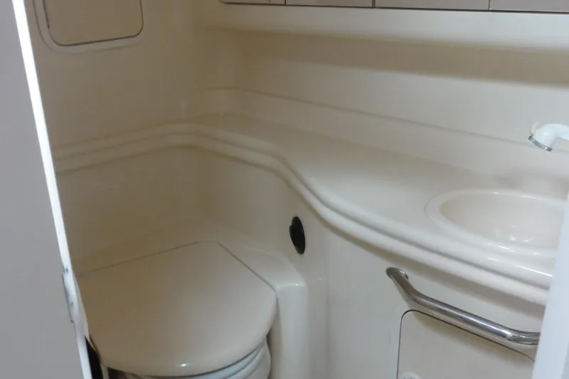 Slide: The Image of 2004 Sea Ray 320 Sundancer bathroom with toilet and sink, compact marine design. - 21