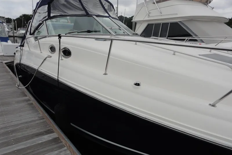 Slide: The Image of 2004 Sea Ray 320 Sundancer docked at marina, showcasing sleek design and white exterior. - 4