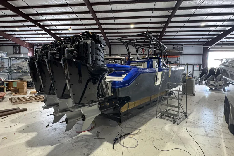 Slide: The Image of 2026 Nor-Tech 390 Sport Center Console boat in a warehouse, featuring multiple outboard engines. - 19