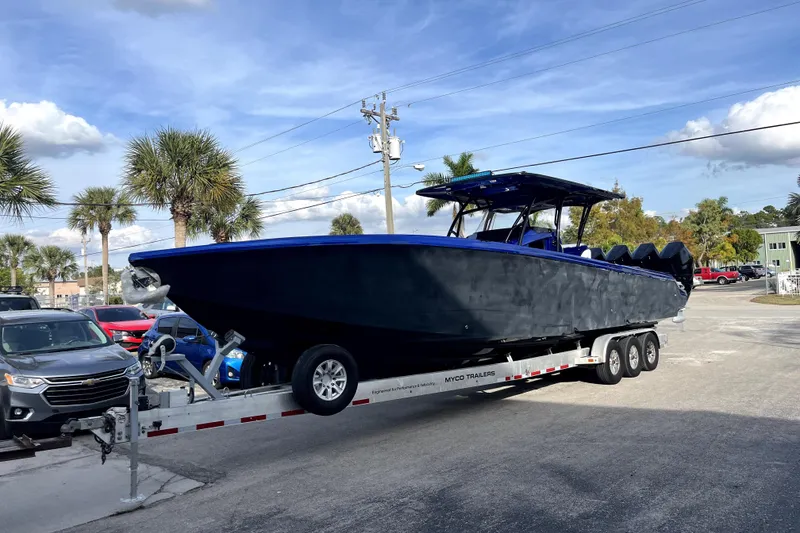 Slide: The Image of 2026 Nor-Tech 390 Sport Center Console boat on trailer in a metal garage. - 2