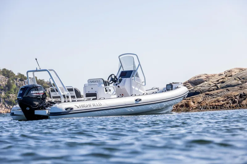 Slide: The Image of 2026 Highfield Sport 560 boat on water near rocky shore, featuring Mercury engine. - 5