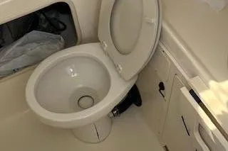 Slide: The Image of 2006 Boston Whaler 320 Outrage Cuddy Cabin bathroom with toilet and storage. - 27