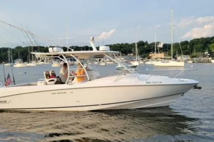 Slide: The Image of 2006 Boston Whaler 320 Outrage Cuddy Cabin on calm water with scenic background. - 6