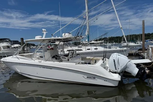 Slide: The Image of 2006 Boston Whaler 320 Outrage Cuddy Cabin docked at marina, clear sky background. - 8