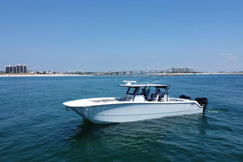 Slide: The Image of 2022 Invincible 46 Catamaran cruising on open water near a coastal cityscape. - 2