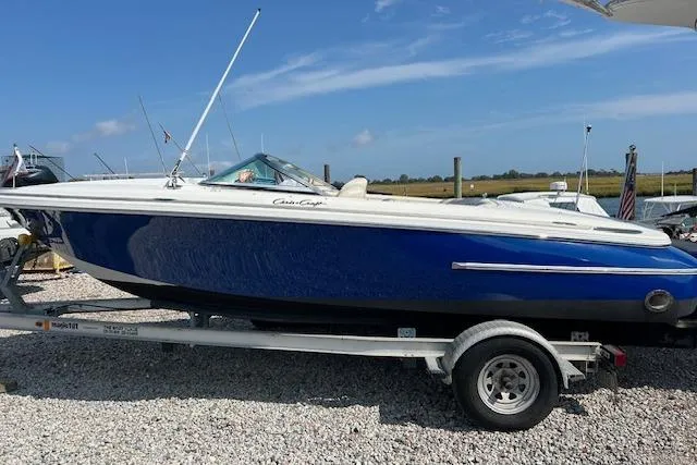 Slide: The Image of 2005 Chris-Craft Speedster boat on trailer, blue and white, parked on gravel. - 2
