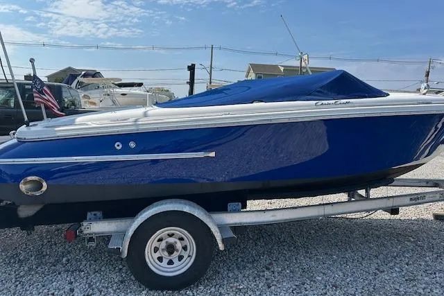 Slide: The Image of 2005 Chris-Craft Speedster boat on trailer, covered in blue tarp, parked on gravel. - 3