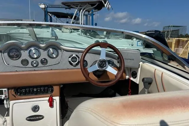 Slide: The Image of 2005 Chris-Craft Speedster boat dashboard with steering wheel and gauges under clear blue sky. - 9