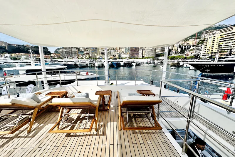 Slide: The Image of Luxurious 2023 Majesty 120 yacht deck with sun loungers, overlooking a marina. - 3