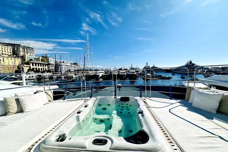 Slide: The Image of Luxurious 2023 Majesty 120 yacht with jacuzzi, docked in a scenic marina under a clear blue sky. - 5