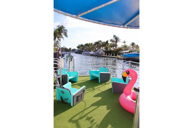 Slide: The Image of 2023 Maurell Pontoon with turquoise seating and pink flamingo float on a sunny day. - 6