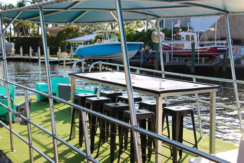 Slide: The Image of 2023 Maurell Pontoon boat with seating and table, docked by waterfront. - 7