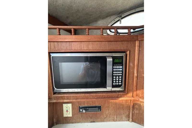 Slide: The Image of Microwave in 1995 Carolina Classic 28 boat interior, wooden cabinetry, and electrical outlet. - 14