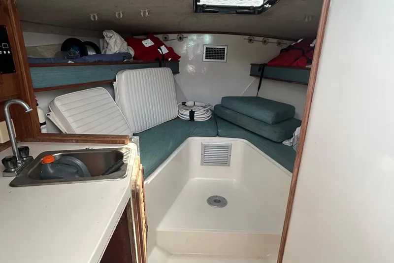 Slide: The Image of Interior of a 1995 Carolina Classic 28 boat, featuring a compact cabin with seating and a sink. - 2