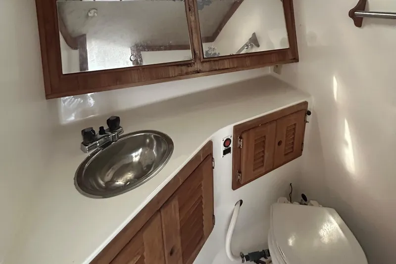 Slide: The Image of 1995 Carolina Classic 28 boat bathroom with sink, mirror, and wooden cabinets. - 3