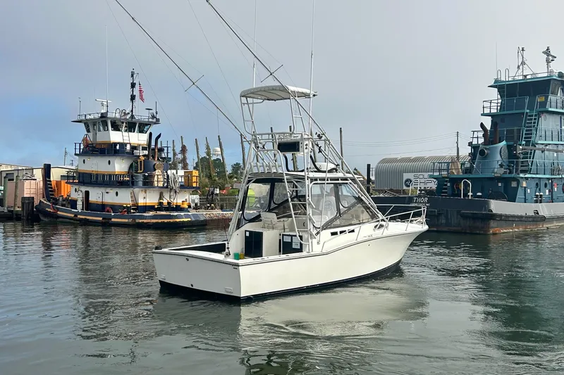 Slide: The Image of 1995 Carolina Classic 28 boat in harbor, with tugboats in the background. - 6