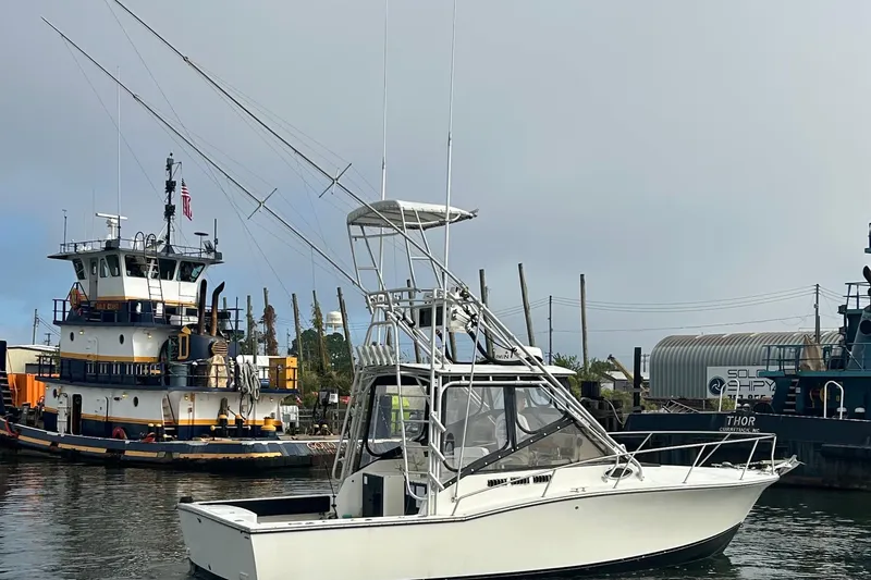 Slide: The Image of 1995 Carolina Classic 28 boat docked near a tugboat in a marina. - 8