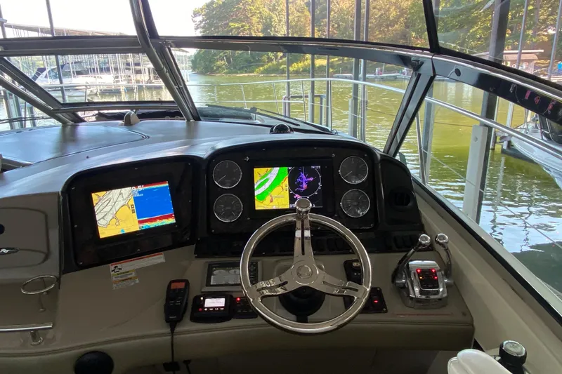 Slide: The Image of Helm of 2008 Sea Ray 44 Sundancer with navigation screens and steering wheel, docked by water. - 7