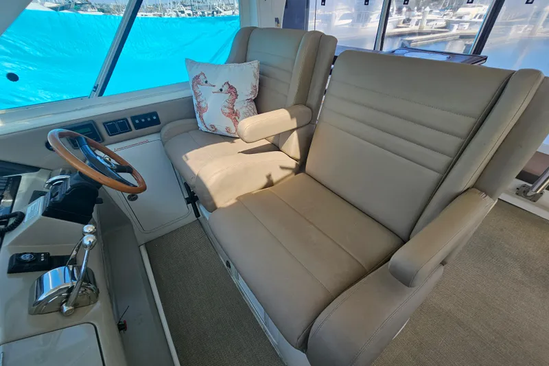 Slide: The Image of 2005 Sea Ray 390 Motor Yacht helm with beige seating and seahorse pillow. - 22
