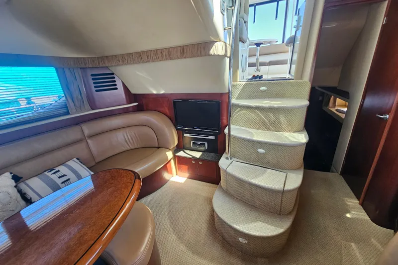 Slide: The Image of 2005 Sea Ray 390 Motor Yacht interior with curved seating, TV, and carpeted stairs. - 26