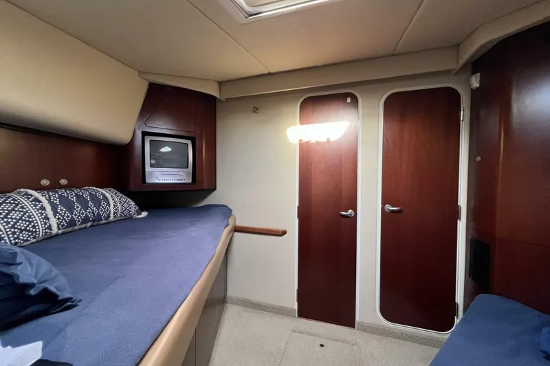 Slide: The Image of 2005 Sea Ray 390 Motor Yacht interior cabin with bed, TV, and wooden doors. - 35
