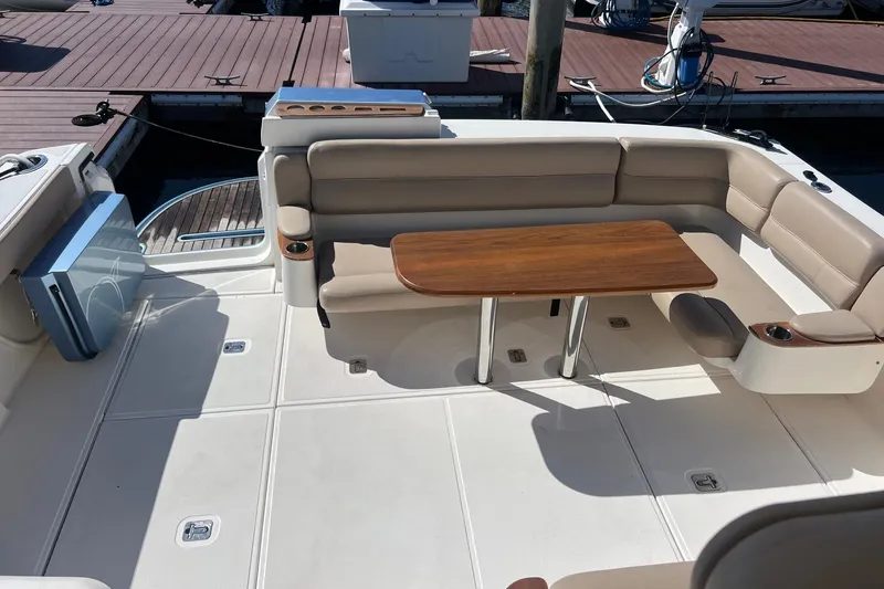 Slide: The Image of 2014 Tiara Yachts 3900 Coronet cockpit with beige seating and wooden table. - 15