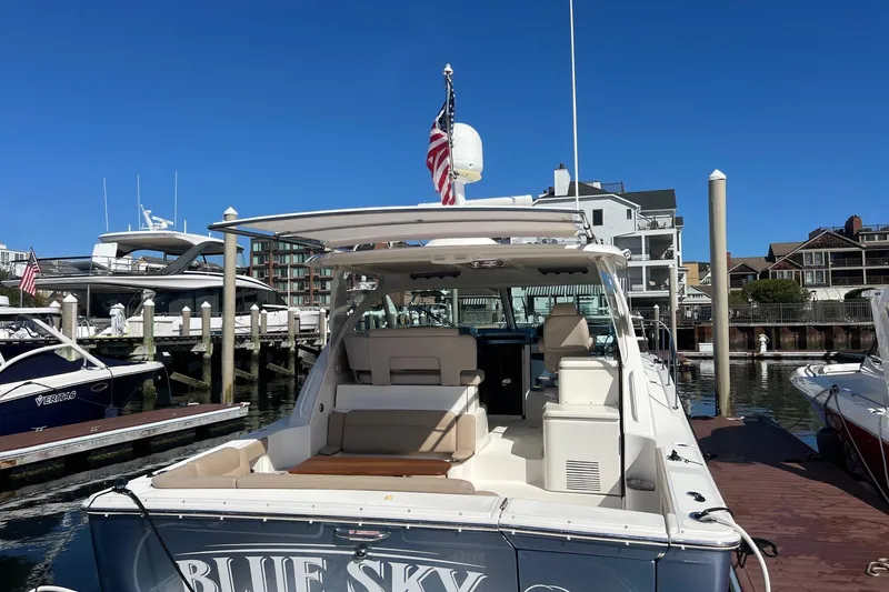 Slide: The Image of 2014 Tiara Yachts 3900 Coronet docked, featuring spacious seating and American flag. - 3