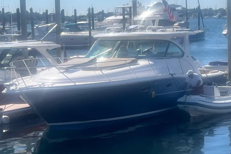 Slide: The Image of 2014 Tiara Yachts 3900 Coronet docked at a marina, with a small boat alongside. - 4