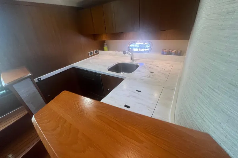 Slide: The Image of 2014 Tiara Yachts 3900 Coronet interior kitchen with wooden cabinetry and marble countertop. - 43