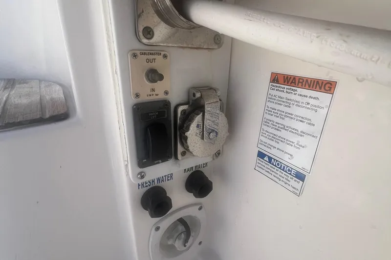 Slide: The Image of Control panel on a 2014 Tiara Yachts 3900 Coronet with warning label and water connections. - 52