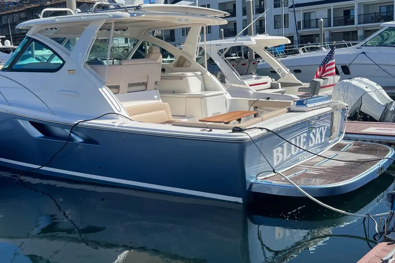 Slide: The Image of 2014 Tiara Yachts 3900 Coronet docked, featuring sleek design and American flag. - 8