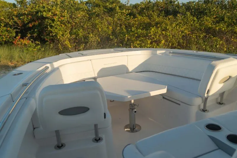 Slide: The Image of 2026 Southport 33 FE boat interior with white seating and table, surrounded by greenery. - 7