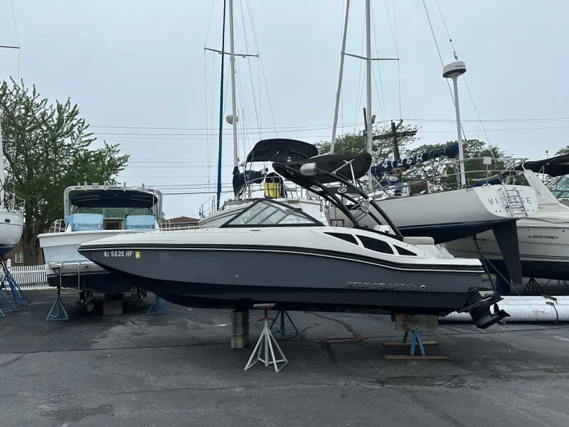 The Image of 2014 Starcraft Crossover 210 SCX IO boat on stands in a marina. - 5