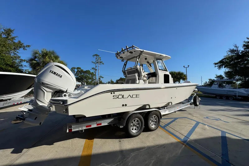 Slide: The Image of 2026 Solace 28 HCS boat on trailer with Yamaha engine, parked outdoors. - 12
