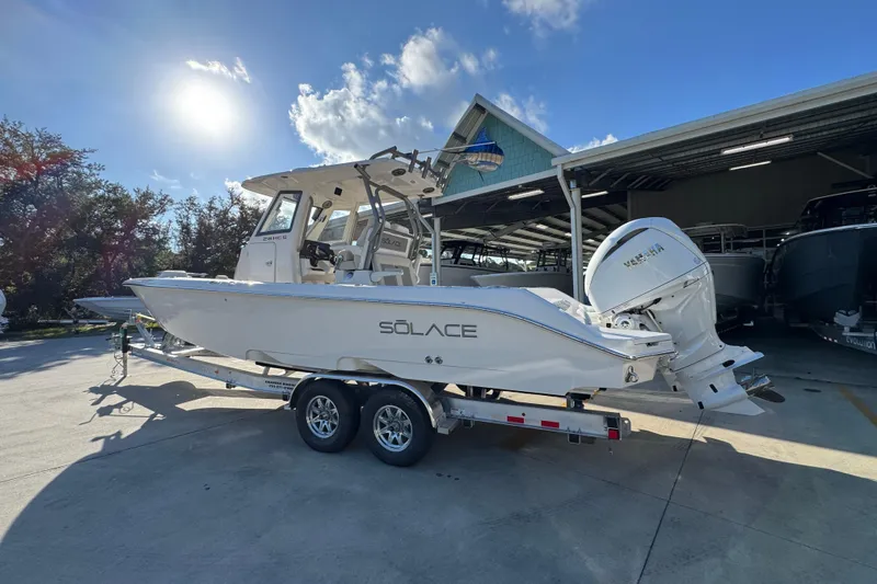 Slide: The Image of 2026 Solace 28 HCS boat on trailer under sunny sky near storage facility. - 18
