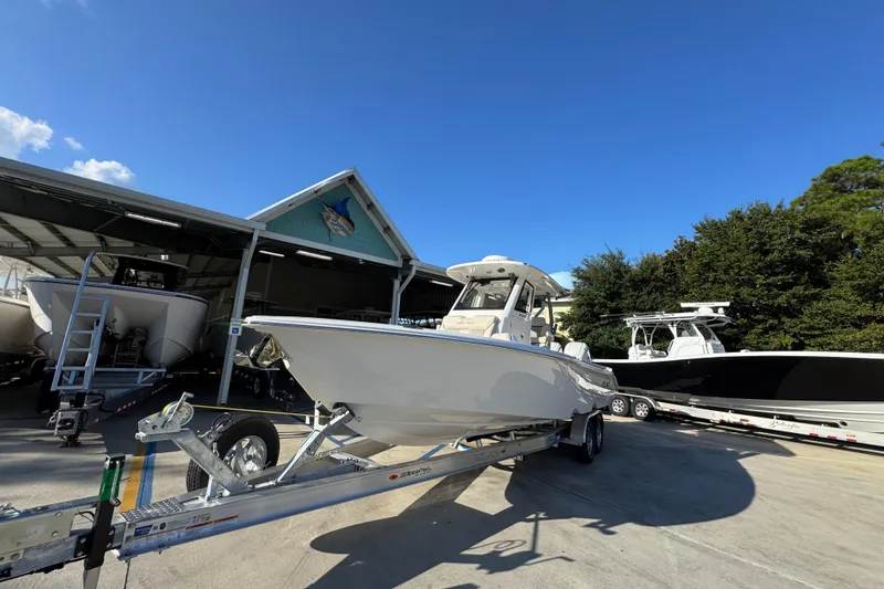 Slide: The Image of 2026 Solace 28 HCS boat on trailer, parked outside a marina under clear blue sky. - 4