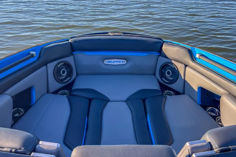 Slide: The Image of 2024 Supra SV 400 boat interior with cushioned seating and speakers on a lake. - 34