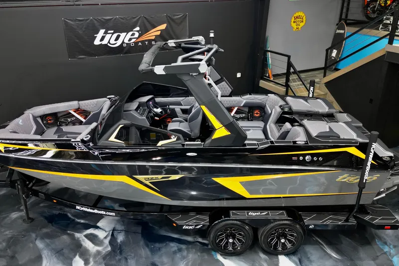 Slide: The Image of 2026 Tigé 22RZX boat in showroom, sleek black and yellow design, luxury seating. - 11