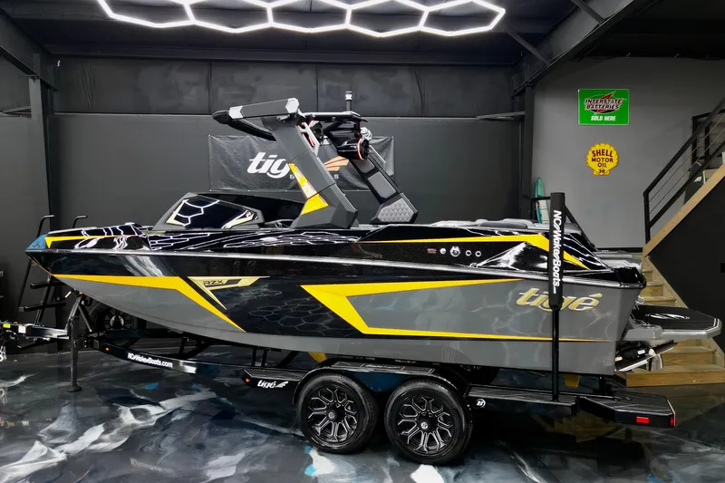 Slide: The Image of 2026 Tigé 22RZX boat in showroom, sleek black and yellow design on trailer. - 26