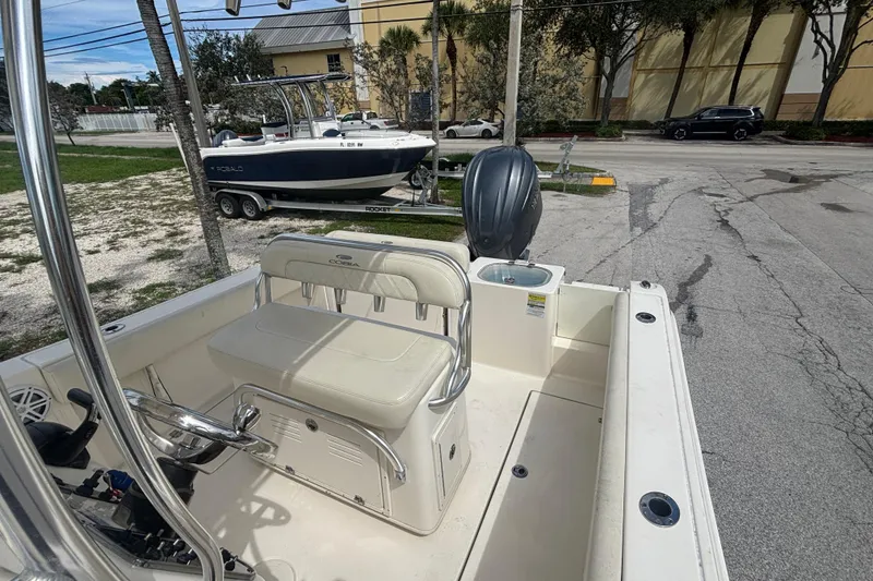 Slide: The Image of 2022 Cobia 237 Center Console boat with seating and outboard motor, parked near a road. - 11