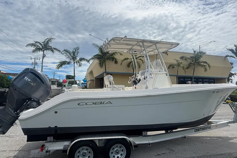 Slide: The Image of 2022 Cobia 237 Center Console boat on trailer, palm trees in background. - 6