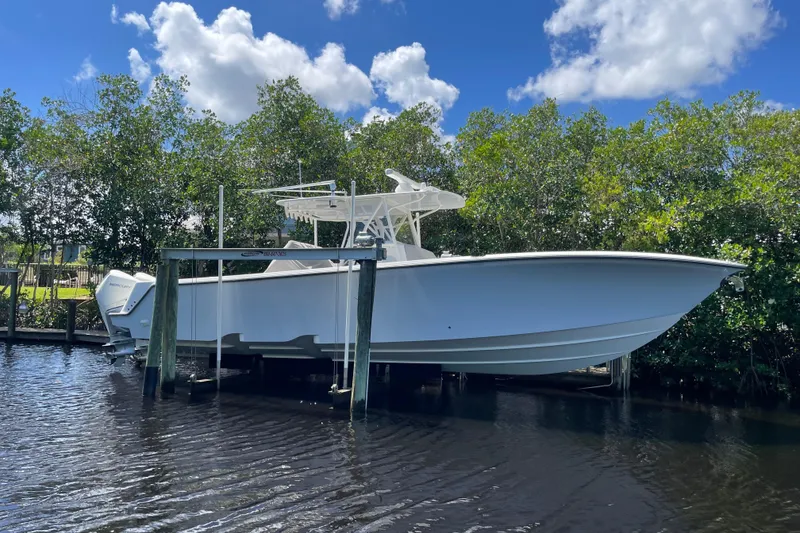 The Image of 2022 SeaVee 370z boat docked on a lift, surrounded by lush greenery and blue sky. - 0