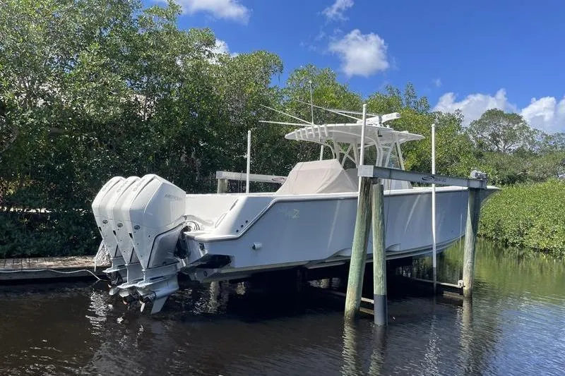 Slide: The Image of 2022 SeaVee 370z boat with triple engines docked near lush greenery. - 2